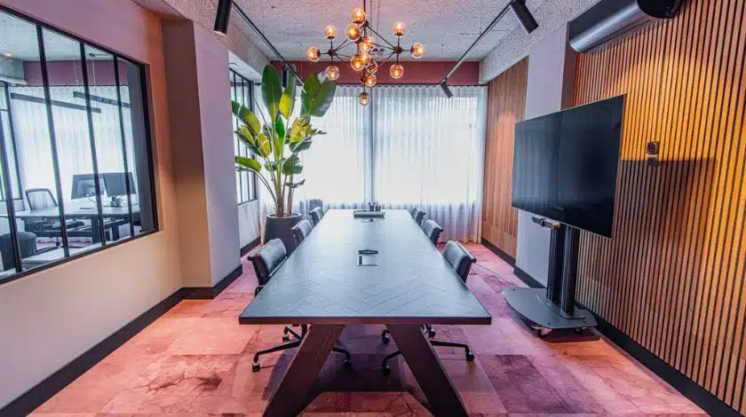 Moderne vergaderruimte met houten akoestische wandpanelen en design tafel, ingericht door E=MC²