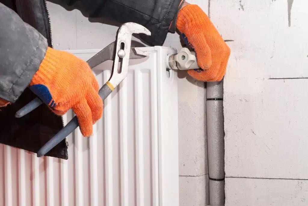 Monteur installeert radiator als onderdeel van werktuigbouwkundige installatie voor energiezuinige klimaatbeheersing in kantoor.