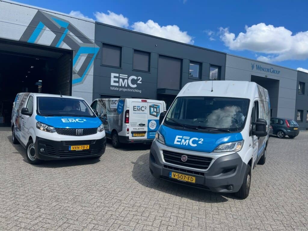 Vooraanzicht E=MC² bedrijfspand met bedrijfsbussen voor projectinrichting en systeemplafonds