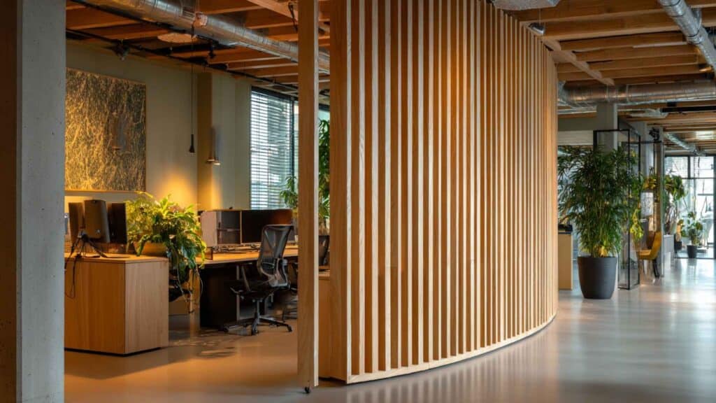 Moderne houten akoestische scheidingswand met lamellen in kantoorinterieur, stijlvol en functioneel voor het creëren van aparte werkplekken.