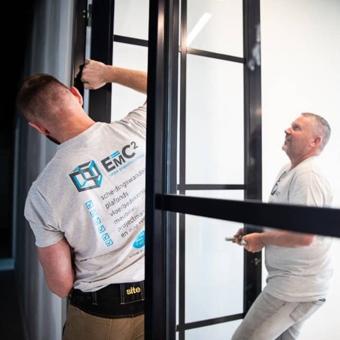 Installers from E=MC² are installing a glass partition wall as part of an office fit-out project