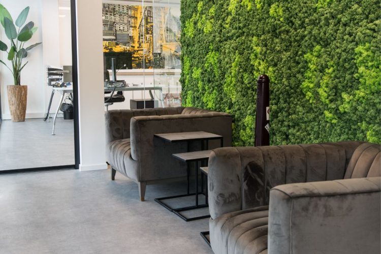 Wachtruimte bij Coffeeclick met groene moswand en moderne loungefauteuils, ingericht door E=MC²
