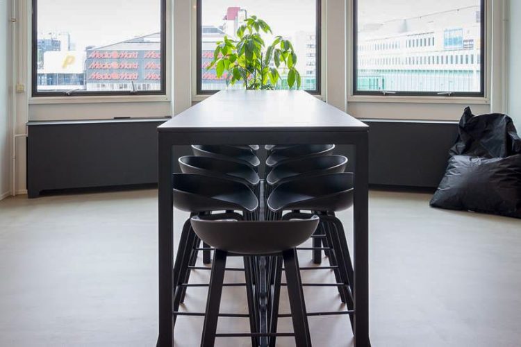 Kantoorinrichting YoungCapital met lange zwarte tafel en moderne barkrukken voor vergaderen of samenwerken