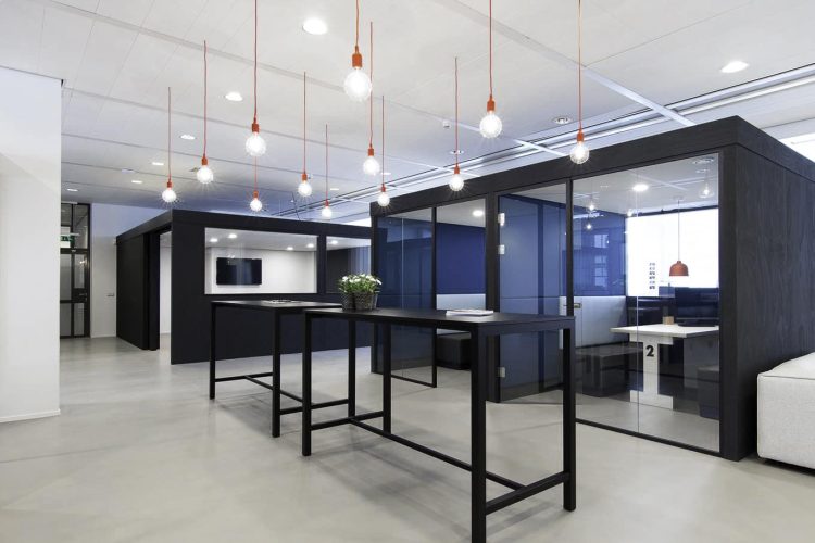 Kantoorinrichting YoungCapital met glazen meetingpods, hoge tafels en moderne verlichting