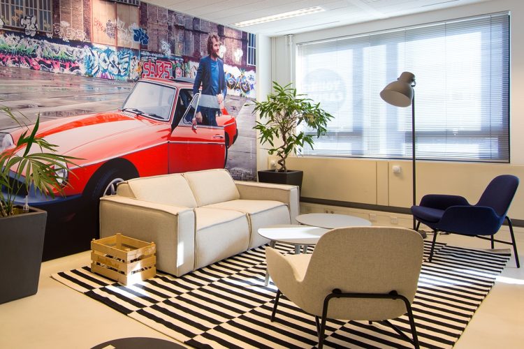 Creatieve loungehoek bij YoungCapital met muurvisual, designmeubilair en projectinrichting